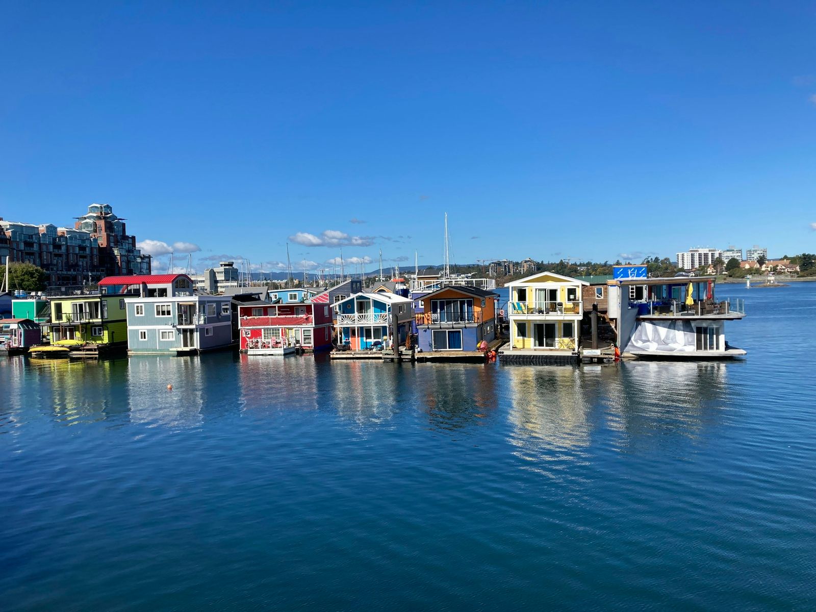 Colourful float homes at Fisherman's Wharf in Victoria reflected in the harbour on a clear autumn day